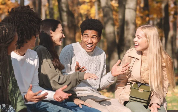 En grupp glada tonåringar som pratar och skrattar i parken — Stockfoto