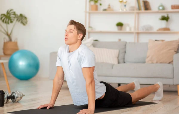 Evde uzaktan yogaya çalış. Kaslı adam paspas üzerinde egzersiz yapıyor. — Stok fotoğraf