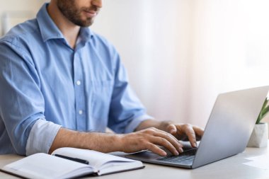 Sakallı Adam İçişleri Bakanlığı 'nda dizüstü bilgisayarda çalışıyor, klavyede daktilo yazıyor.