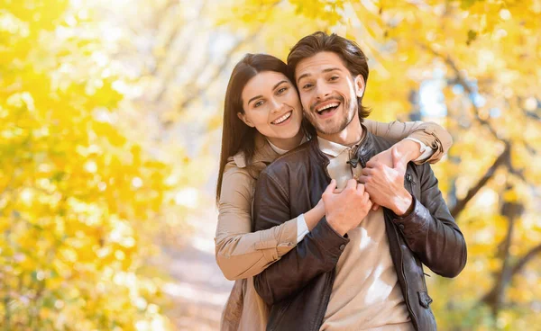 Mujer positiva abrazando a su hombre por detrás, posando en el parque —  Fotos de Stock