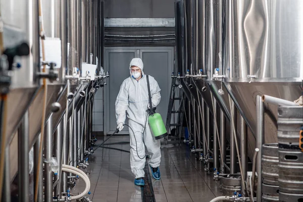 Brasseur travaillant avec des équipements industriels à la brasserie en combinaison de protection et nettoie — Photo