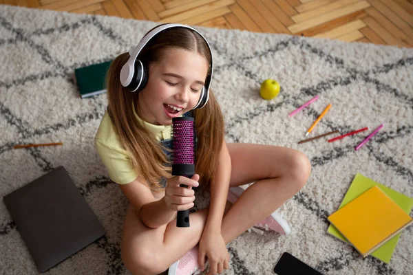 Meisje luisteren naar muziek en zingen in penseel — Stockfoto