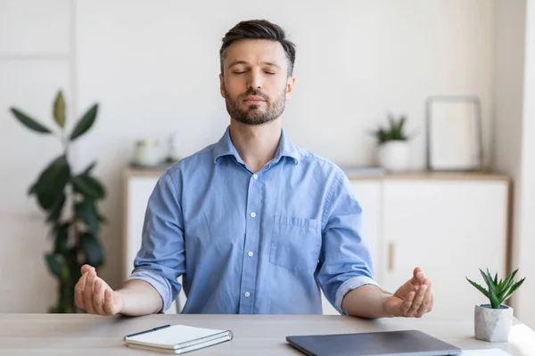 Офіс Дзен. Розслаблений чоловік підприємець медитує на робочому місці, впорається зі стресом роботи — стокове фото