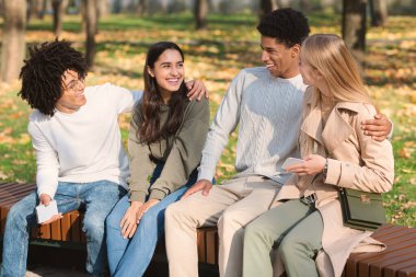 Halk parkında bankta oturan iki çift öğrenci.