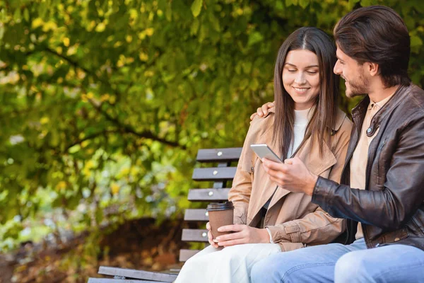 Uomo e donna seduti sulla panchina e a guardare le foto — Foto Stock