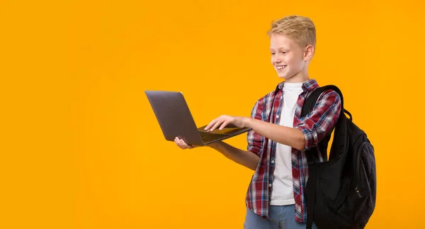 Szczęśliwy facet trzyma laptopa w żółtym studio ściany — Zdjęcie stockowe