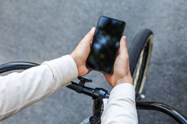 Şehirdeki sosyal ağlar. Bisiklette oturan ve akıllı telefona bakan adam.