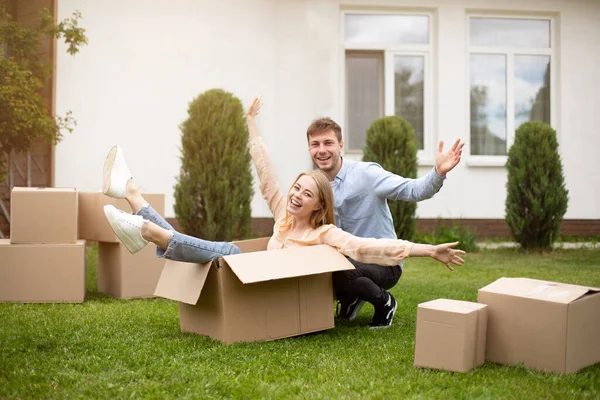 Dom jong paar spelen met kartonnen doos in de buurt van nieuw huis op bewegende dag — Stockfoto