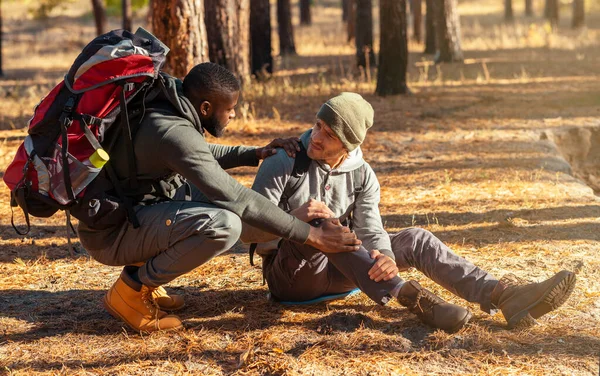 Black guy helping his injured friend, hiking together