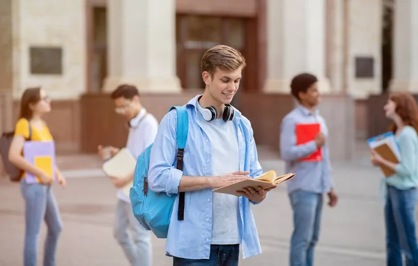 Università studente ragazzo lettura libro apprendimento in piedi al di fuori College Building — Foto Stock