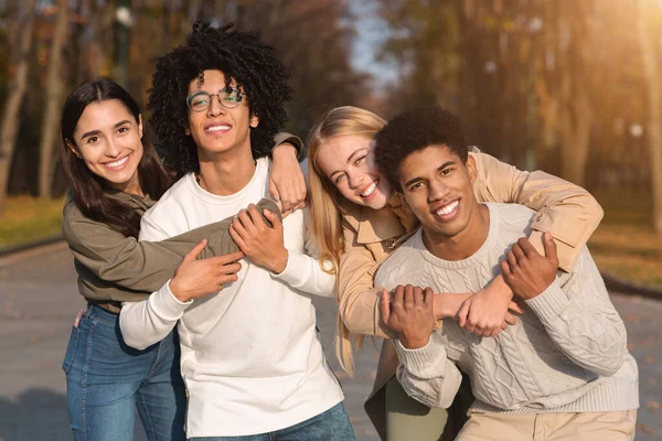 Dos parejas adolescentes multirraciales acurrucándose en el parque —  Fotos de Stock