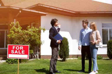 Ev temsilcisi dışarıda potansiyel alıcılara yeni bir mülk gösteriyor. Boşluk alanı