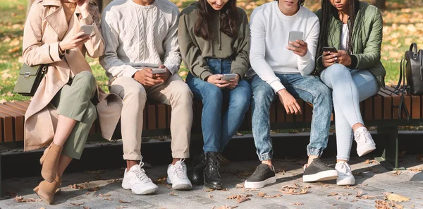 Grupa międzynarodowych nastolatków korzystających ze smartfonów w parku — Zdjęcie stockowe