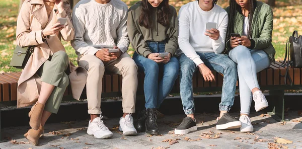 Parkta akıllı telefon kullanan bir grup uluslararası genç. — Stok fotoğraf