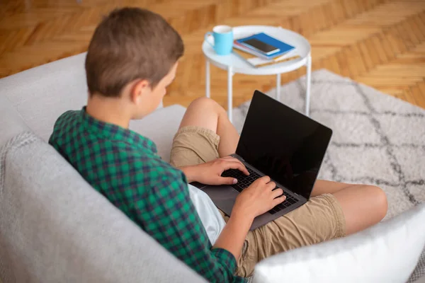 Boş ekranlı dizüstü bilgisayar kullanan genç, evde oturuyor — Stok fotoğraf