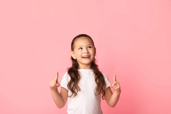 Feliz ásia menina apontando dedos até no cópia espaço — Fotografia de Stock