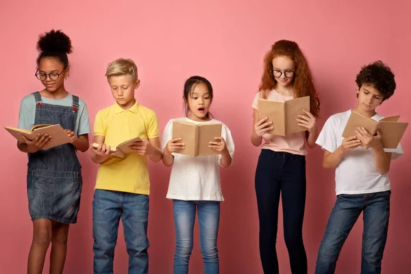 Focado diversas crianças em idade escolar lendo livros sobre fundo rosa — Fotografia de Stock