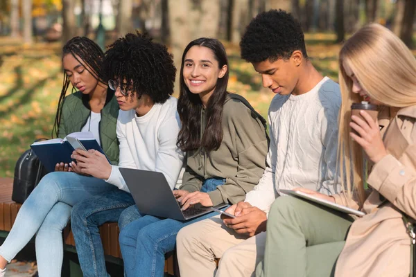 Amigos adolescentes estudiando al aire libre, usando aparatos y leyendo libros — Foto de Stock