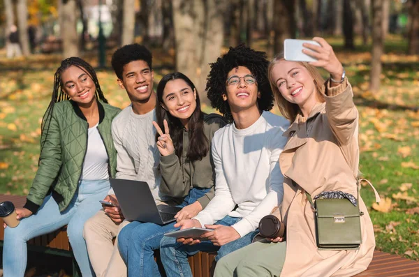 Neşeli gençler bankta oturup selfie çekiyorlar. — Stok fotoğraf