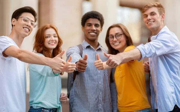 Estudiantes haciendo gestos para arriba aprobando la universidad de pie al aire libre —  Fotos de Stock