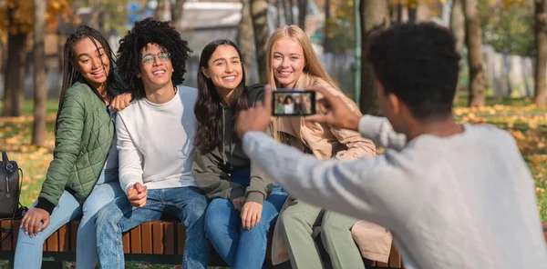 Svart kille tar kort på sina vänner, med hjälp av smartphone — Stockfoto