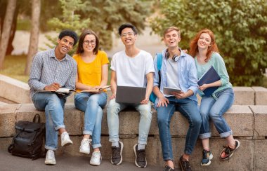 Mutlu Çeşitli Öğrenciler Dışarıda Birlikte Oturuyor, Kameraya Gülümsüyor