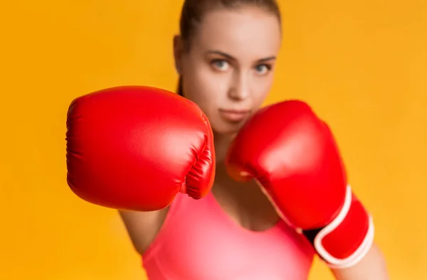 Νέοι Sporty κορίτσι φορώντας κόκκινα γάντια πυγμαχίας, κάνοντας χειρονομίες γάντζο — Φωτογραφία Αρχείου