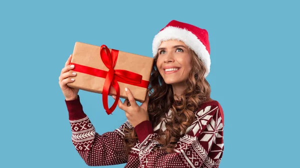 Compras de Navidad. Mujer bastante milenaria sosteniendo gran regalo de Navidad sobre fondo azul — Foto de Stock