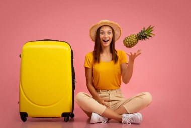 Ananaslı kız bagajın yanında oturuyor.