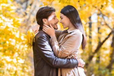 Sevgi dolu bir kız parkta sarılırken sevgilisinin yüzüne dokunuyor.