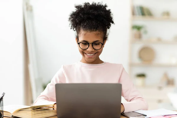 Menina adolescente africana feliz estudando no computador portátil em casa — Fotografia de Stock