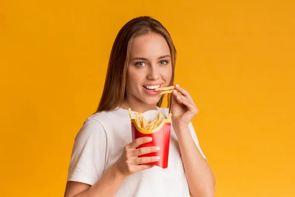 Patates kızartması yiyen mutlu genç kadının portresi. — Stok fotoğraf