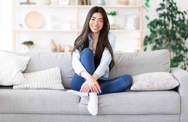 Retrato de menina coreana sorridente relaxado posando no sofá em casa — Fotografia de Stock