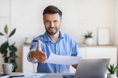 İş görüşmesi için. Arkadaş canlısı erkek İK yöneticisi kamerada el sıkışmak için elini uzatıyor.