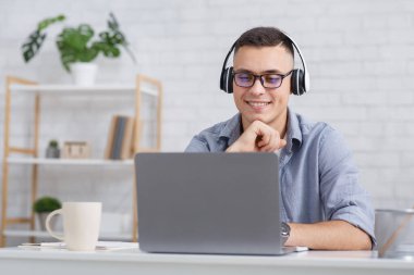 Covid-19 karantinası sırasında evdeki öğrenci ya da çalışan. Neşeli adam internetten bilgisayar dersi izliyor.