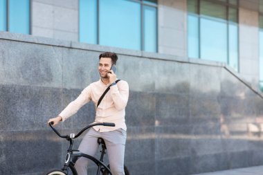 Yolculuk sırasında akıllı telefondan iletişim. Bisikletli genç iş adamı