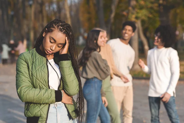 Sconvolto teen nero ragazza con amici pettegolezzi in background — Foto Stock