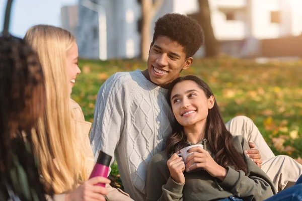 Casal adolescente multiétnico fazendo piquenique com amigos no parque — Fotografia de Stock