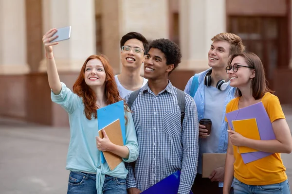 Feliz estudiante chica haciendo grupo selfie con cursados de pie al aire libre —  Fotos de Stock