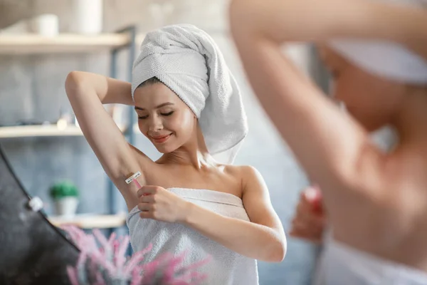 Mooi millennial meisje scheren haar oksel in de buurt spiegel op badkamer — Stockfoto