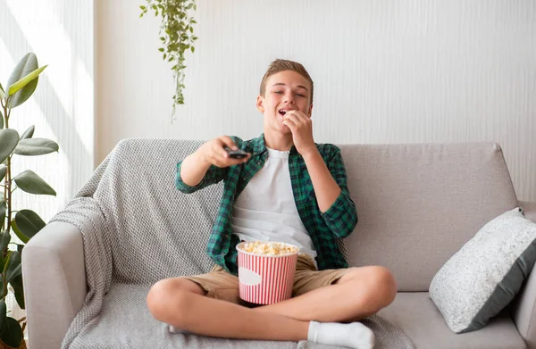 Adolescent joyeux regarder la télévision seul, manger du pop-corn — Photo