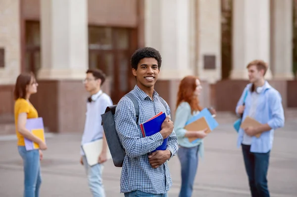 Heureux étudiant africain posant avec des livres debout près de l'université en plein air — Photo