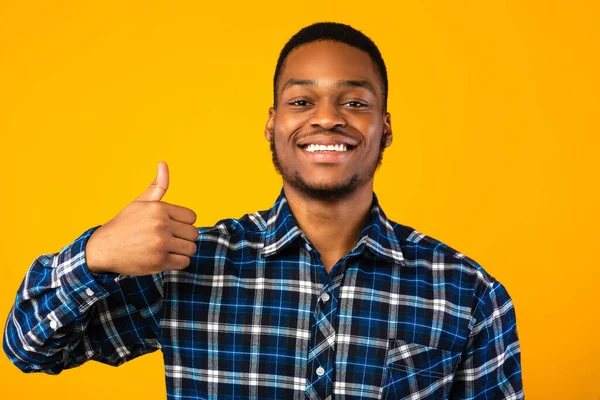 Pozitív afrikai férfi Gesturing hüvelykujj-up álló felett sárga háttér — Stock Fotó
