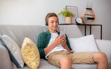 Neşeli okul çocuğu cep telefonundan video izliyor.