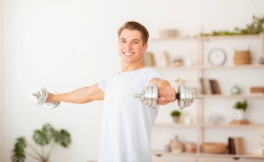 Karantina altındayken vücut bakımı. Gülümseyen yakışıklı adam spor malzemeleriyle sabah antrenmanı yapıyor.