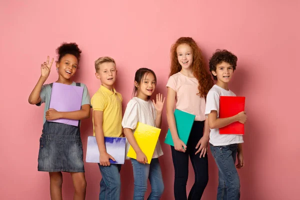 Retrato de estudiantes de escuela feliz con copybooks sonriendo sobre fondo rosa — Foto de Stock