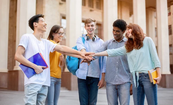 Studenten die handen vasthouden in een cirkel buiten het universiteitsgebouw — Stockfoto