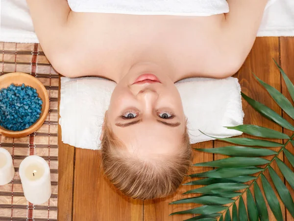 Wellness centrum. Dívka leží na masážním stole, vedle soli a lázeňského příslušenství — Stock fotografie