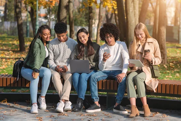 Adolescentes viciados usando gadgets enquanto passam o tempo no parque — Fotografia de Stock