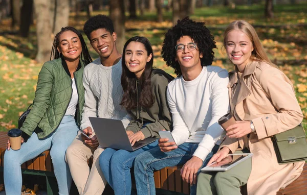 Χαρούμενοι έφηβοι φίλοι κάθονται στον πάγκο με gadgets — Φωτογραφία Αρχείου